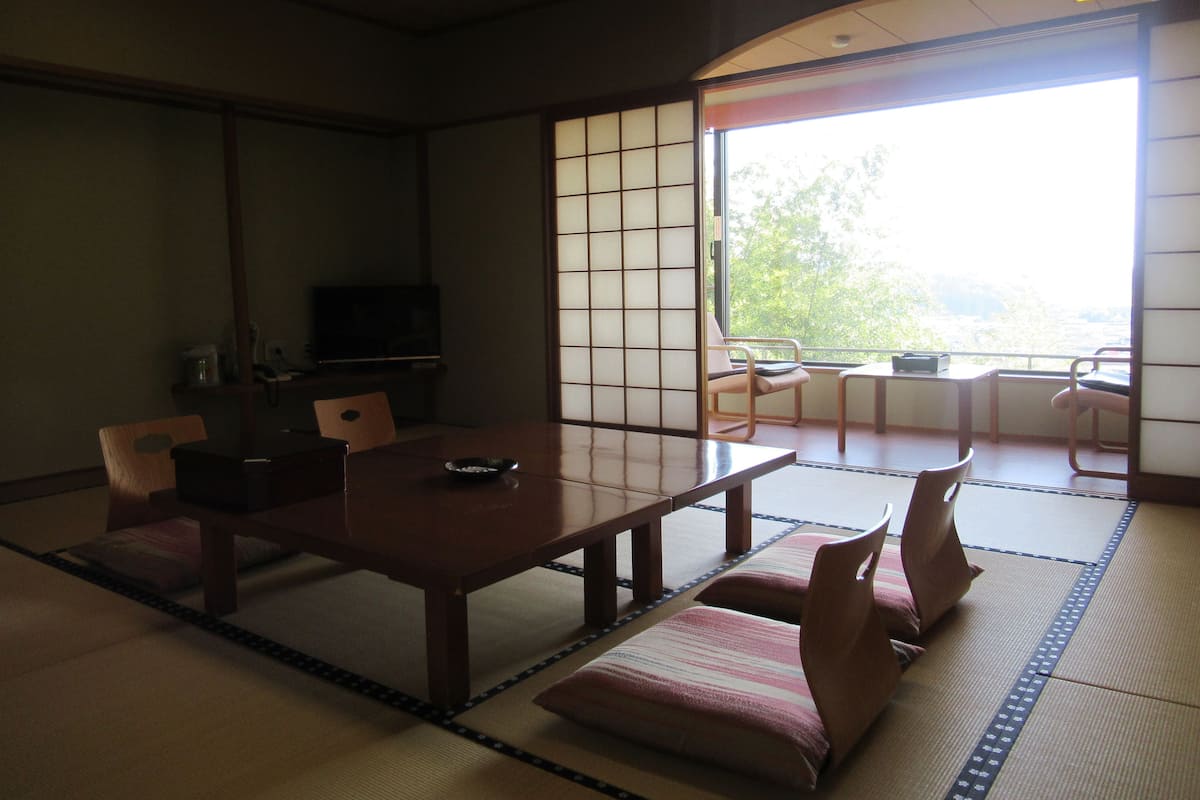 A traditional Japanese room with tatami flooring, a low table, and seating.