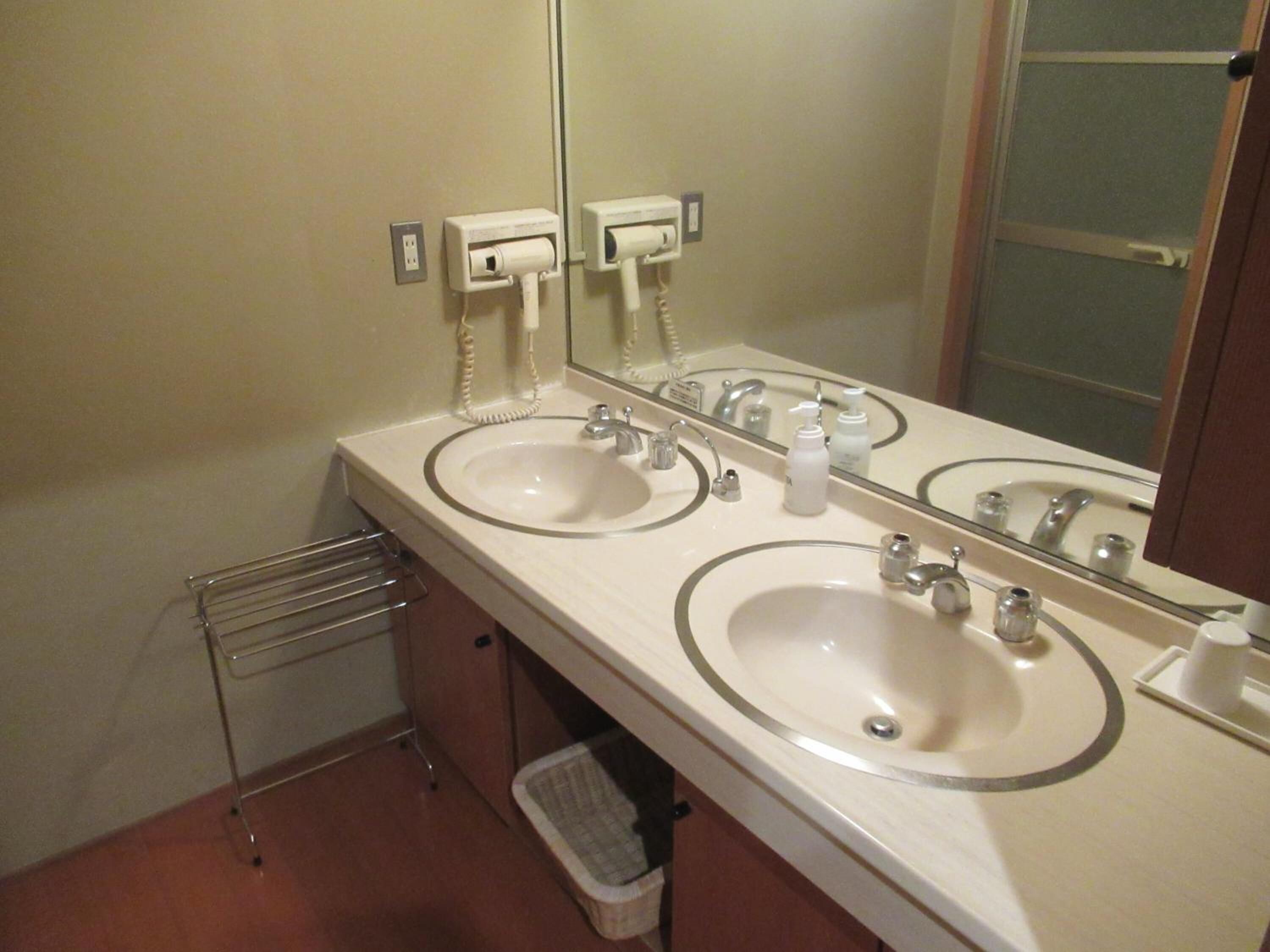 Une salle de bain avec deux lavabos, un miroir, un porte-serviettes et une poubelle.