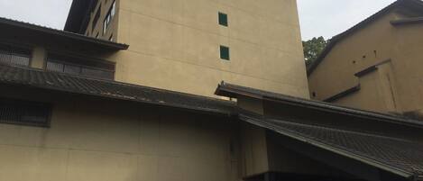 A building with a beige facade, multiple windows, and a traditional tiled roof.