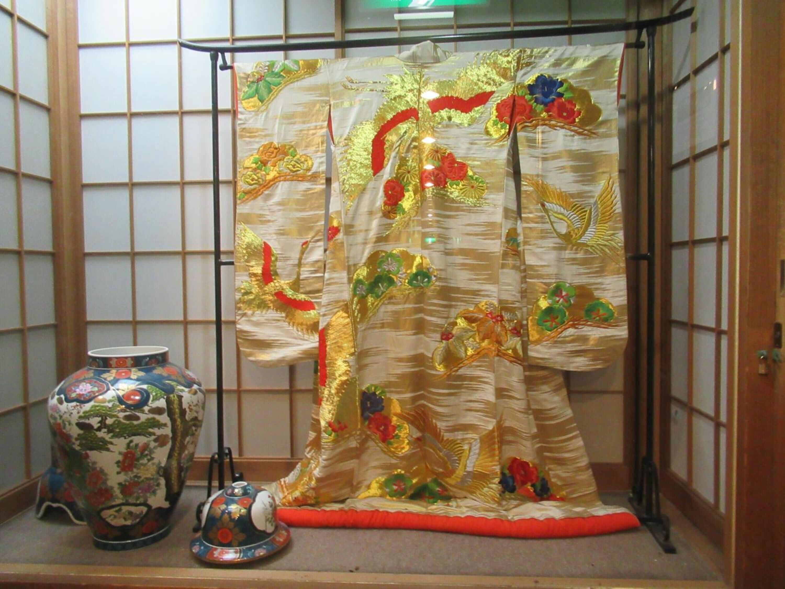 Ein traditioneller japanischer Raum mit Tatami-Boden, Shoji-Schirm, dekorativer Vase und Tee-Set.