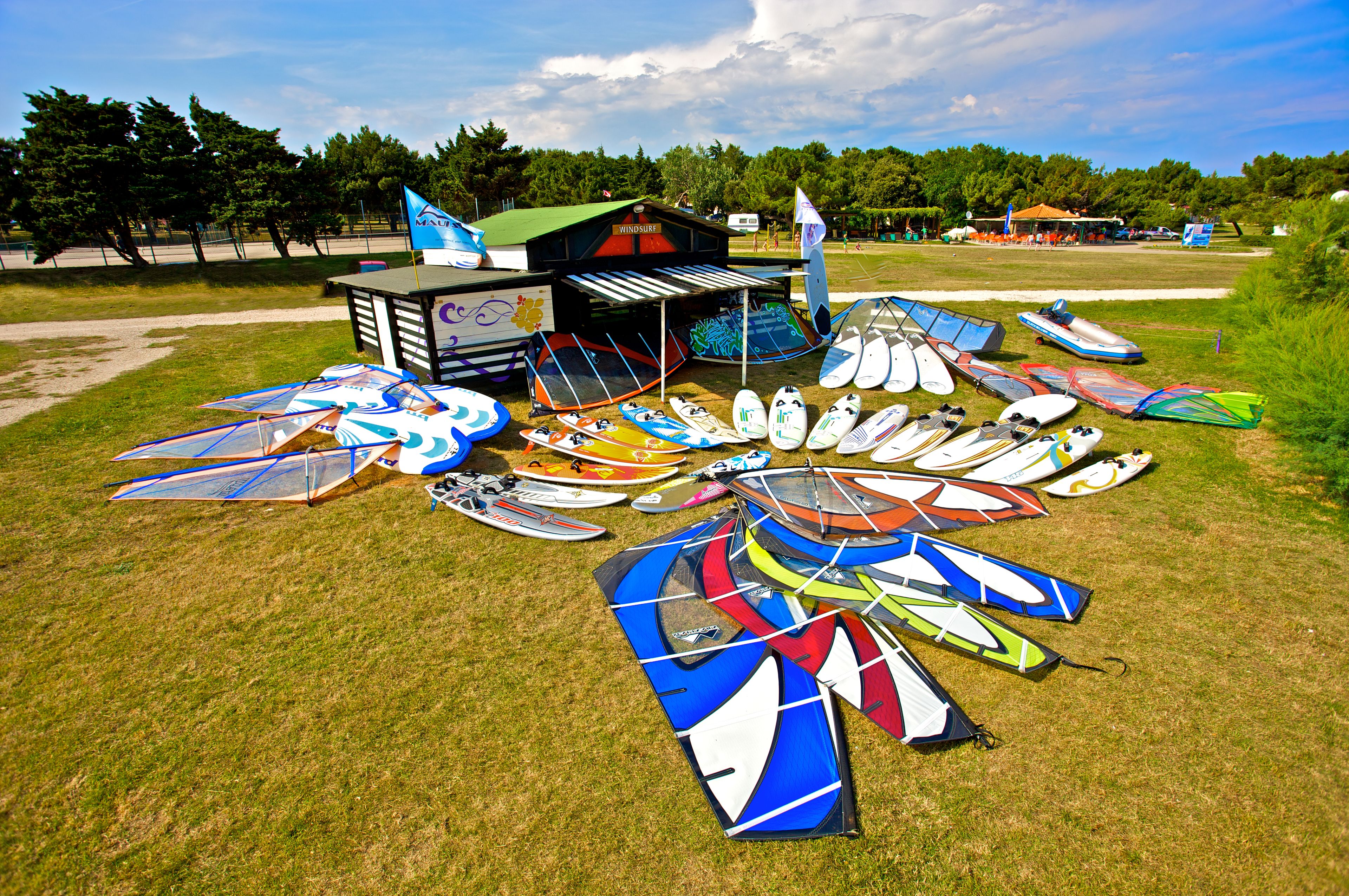 Eine grüne Wiese mit verschiedenen Drachen und Windsurfgeräten.