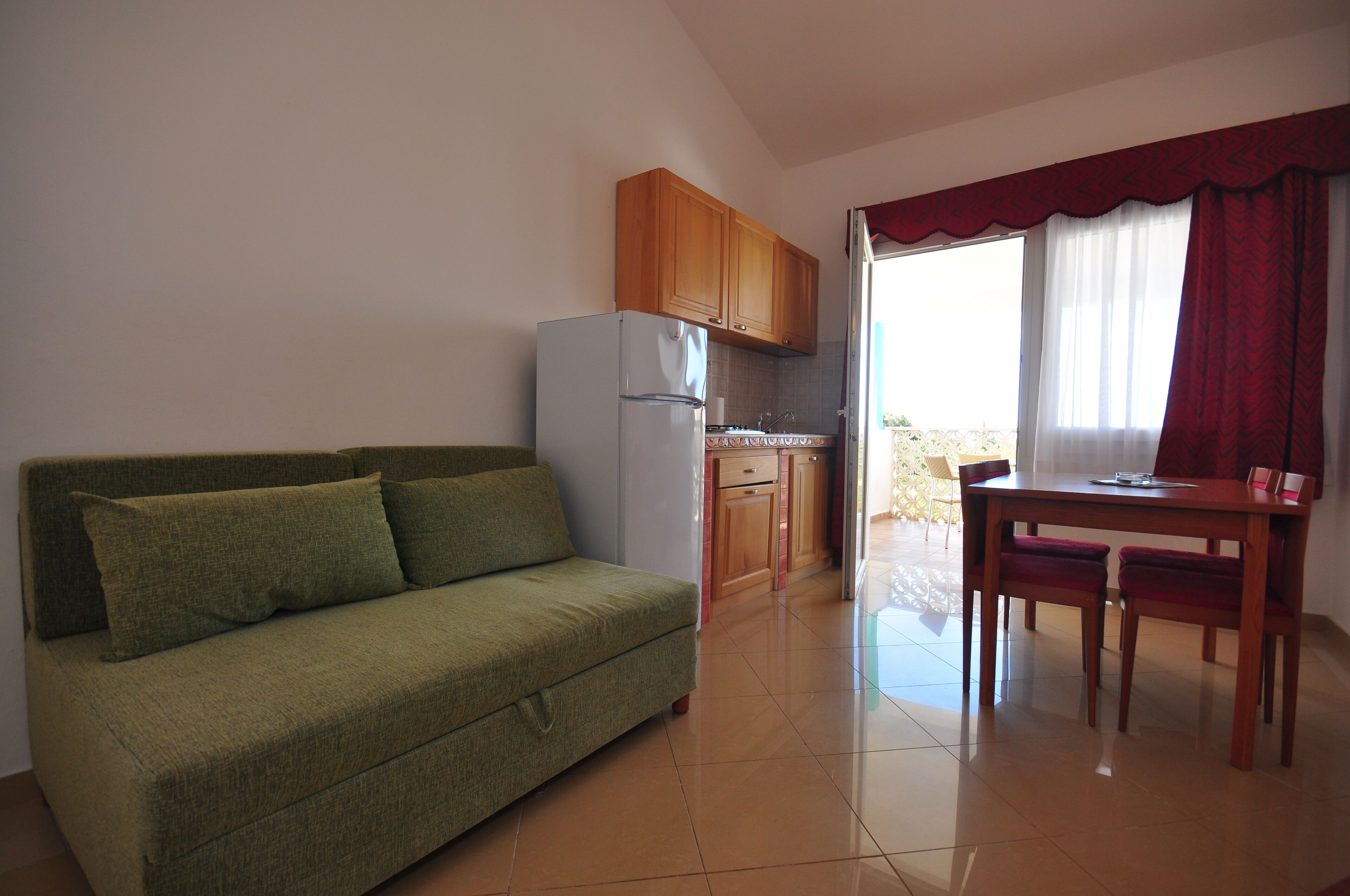 A compact living space with a kitchenette, a dining table, and a sofa.