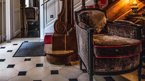 Una amplia escalera con barandilla de madera y alfombra roja que conduce a una habitación con piso estampado.