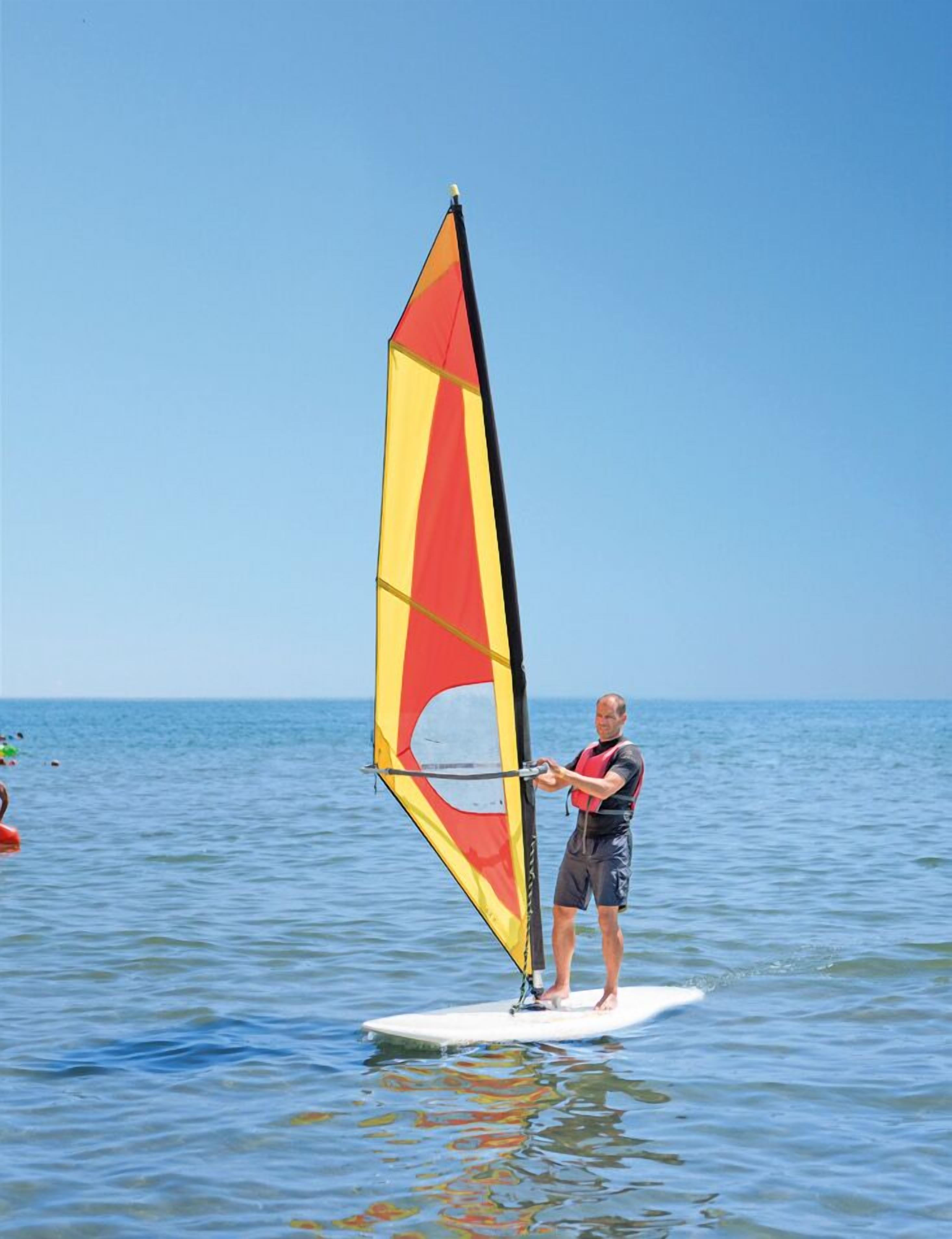 Eine Person windsurft bei strahlendem Sonnenschein.