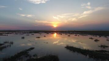 A sunset over a wetland area with water reflecting the sky.