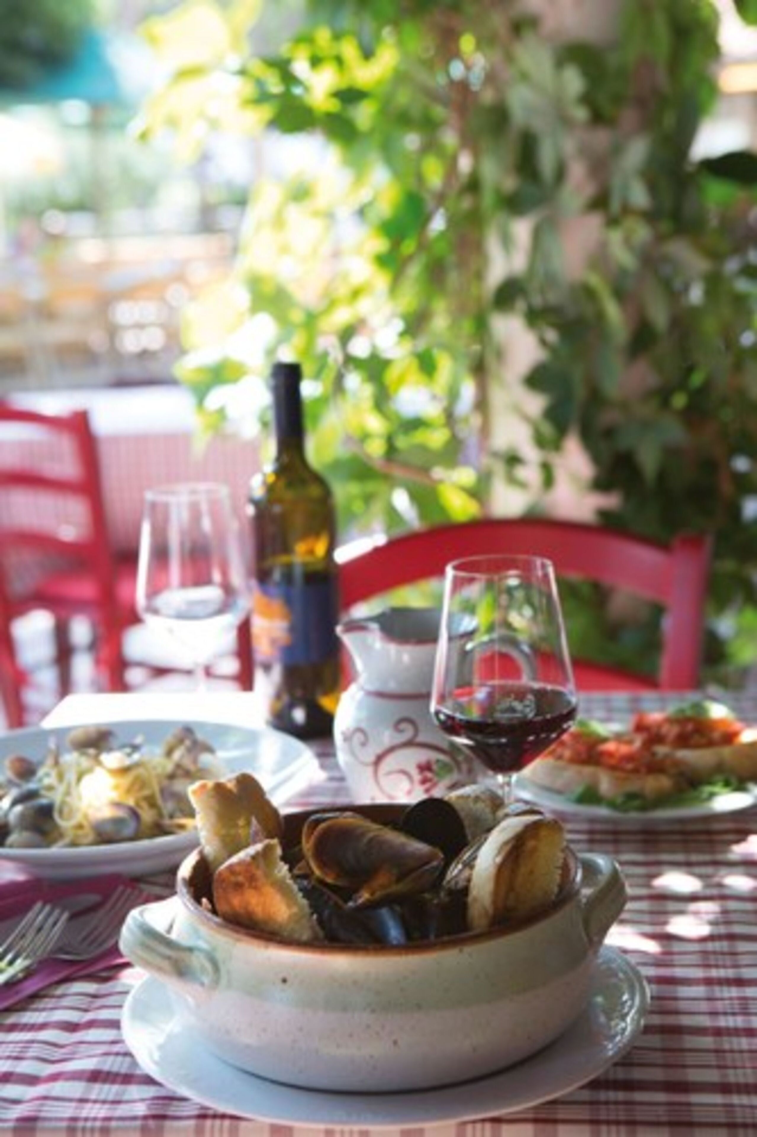A dining table with a bowl of seafood, a wine bottle, and glasses.