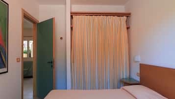 Une chambre à coucher avec un lit, une tête de lit en bois, une table de chevet, une lampe et un rideau à rayures.