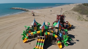 Een strand speeltuin met glijbanen en klimconstructies.