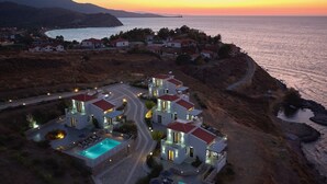 A coastal property with multiple villas, a swimming pool, and a view of the sea at sunset. - Eleia Seafront Rooms & Villas (Lesvos)