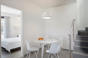 Enjoy a stylish space with a round dining table, white bed, and staircase leading to an upper level.