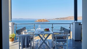 A terrace with a table, chairs, and a view of the sea. - Eleia Seafront Rooms & Villas (Lesvos)
