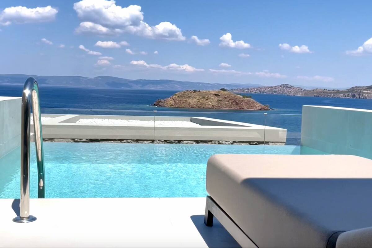 A pool with a view of the sea and a small island.