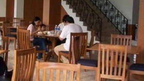 A dining area with wooden chairs and tables, a staircase with a metal railing, and a tiled floor. - Alam Permai (Bandung)