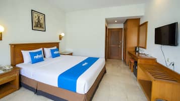 A hotel room with a bed, bedside tables, a desk, a television, and a door leading to another room.