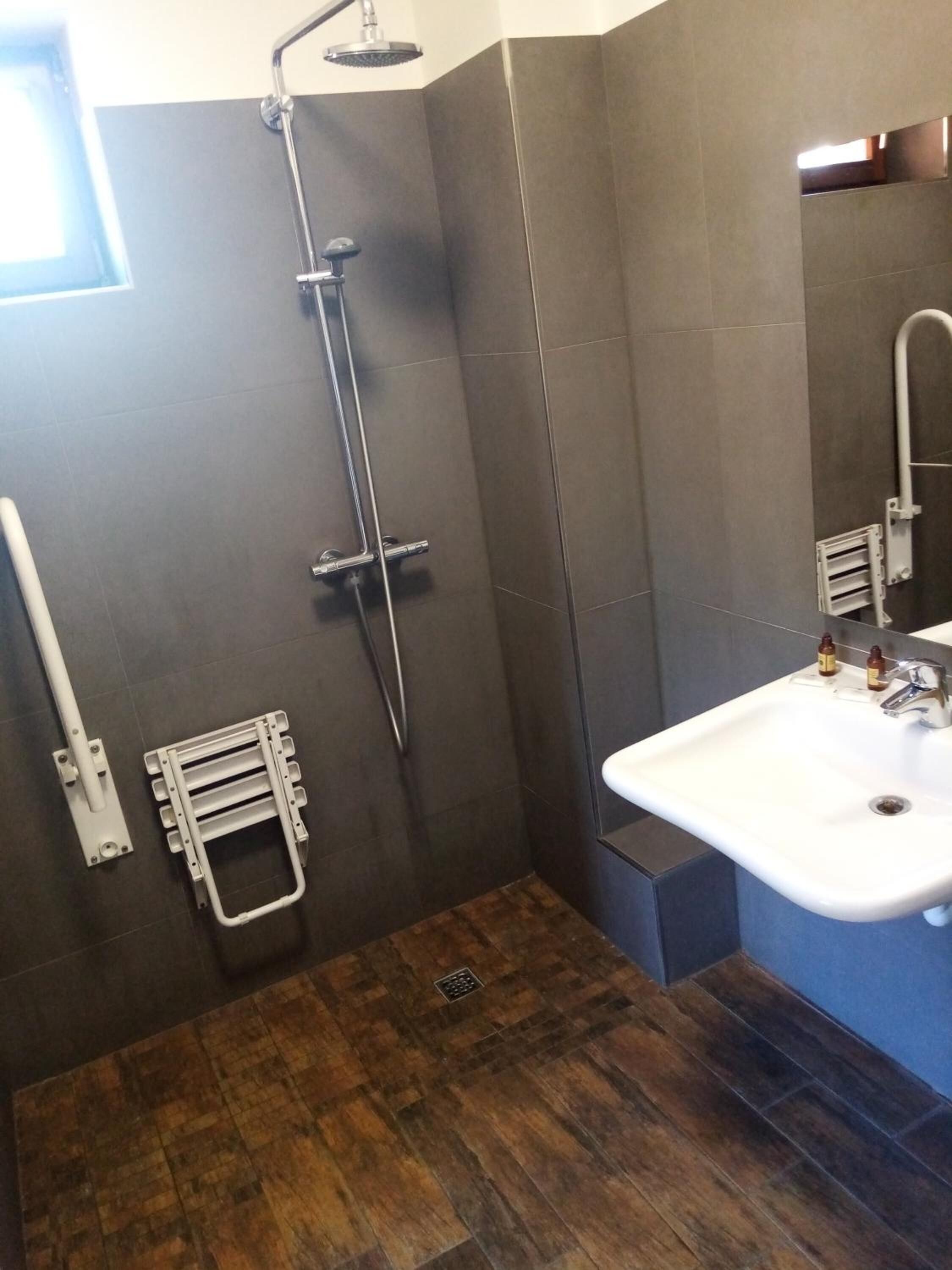 A modern bathroom with a shower, a sink, and a wooden floor.