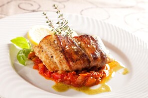 A plate with a grilled fish, lemon, and herbs. - Le Verger De Bischwiller (Bischwiller)