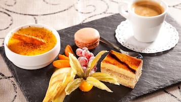 Ett dessertfat med en bit tårta, en skål med vaniljsås och en kopp kaffe, serverat på en skifferbricka.