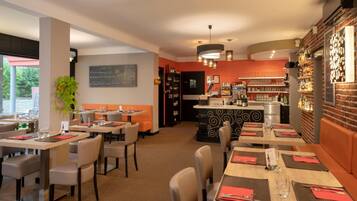 A restaurant with multiple dining tables, chairs, and a bar area.