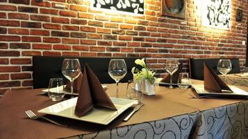 A restaurant with brick walls and a table set for four with wine glasses, plates, and napkins.