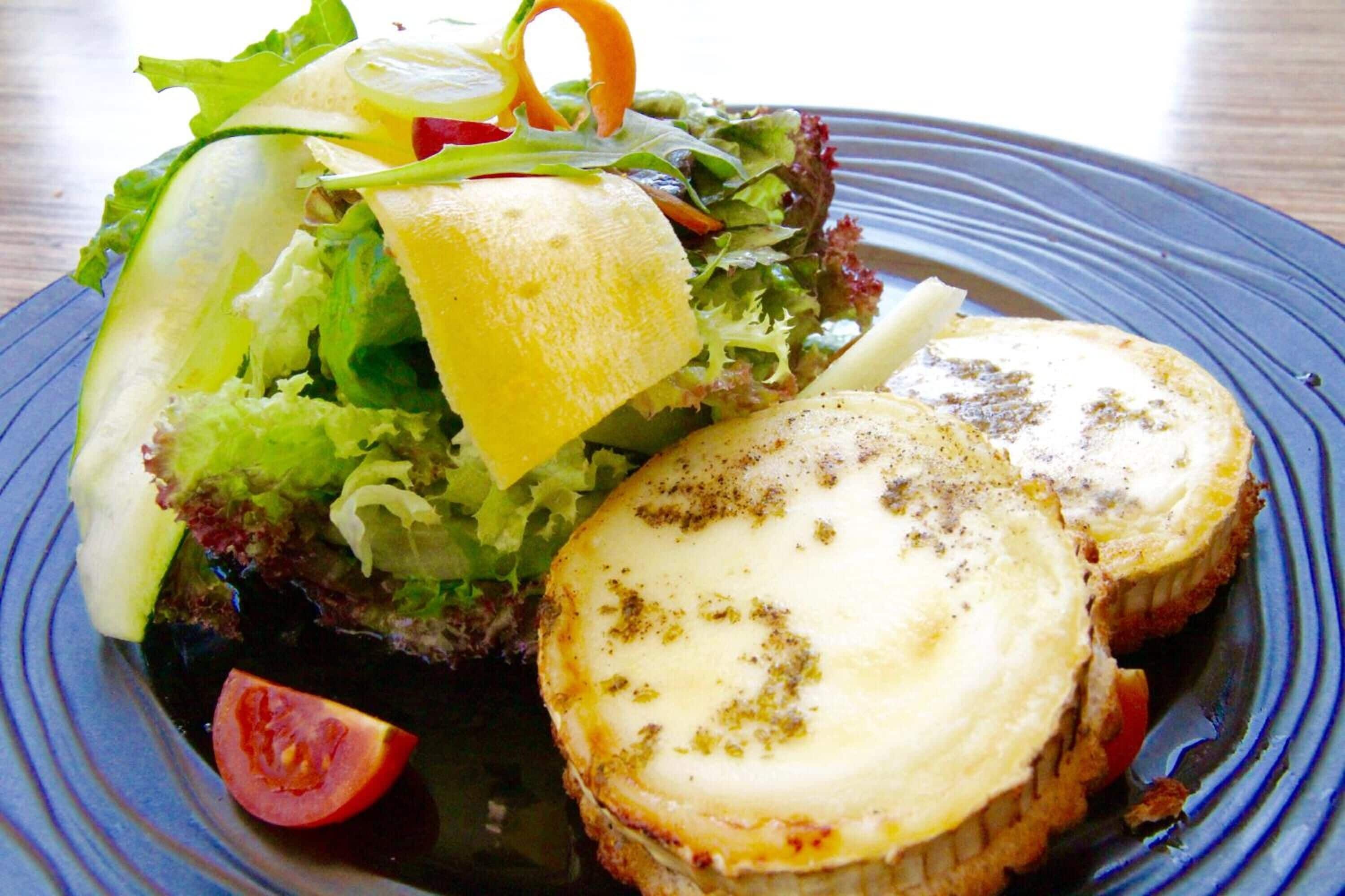 A plate with a salad and a slice of cheese.