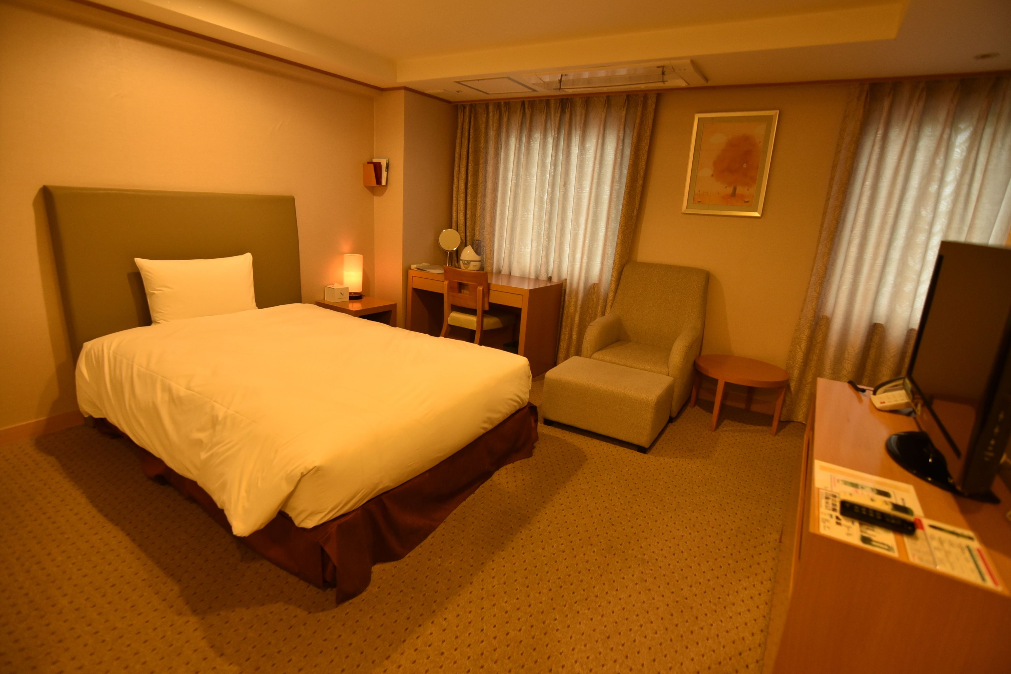 Une chambre d’hôtel avec un grand lit, un bureau avec une chaise, une télévision et une petite table.