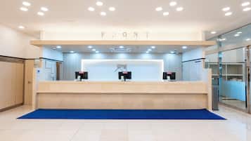 A reception desk with a blue carpet, a sign above it, and a counter with a computer.