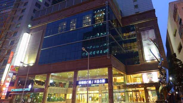 A hotel with a modern glass facade, multiple floors, and a prominent 'HOTEL' sign at the top.