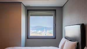 A hotel room with a large window, a bed, and a headboard.