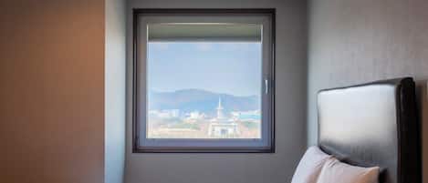 A hotel room with a large window, a bed, and a headboard.