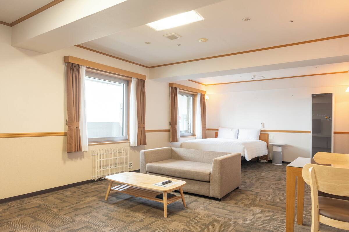 A hotel room with a bed, a sofa, a table, and a chair.