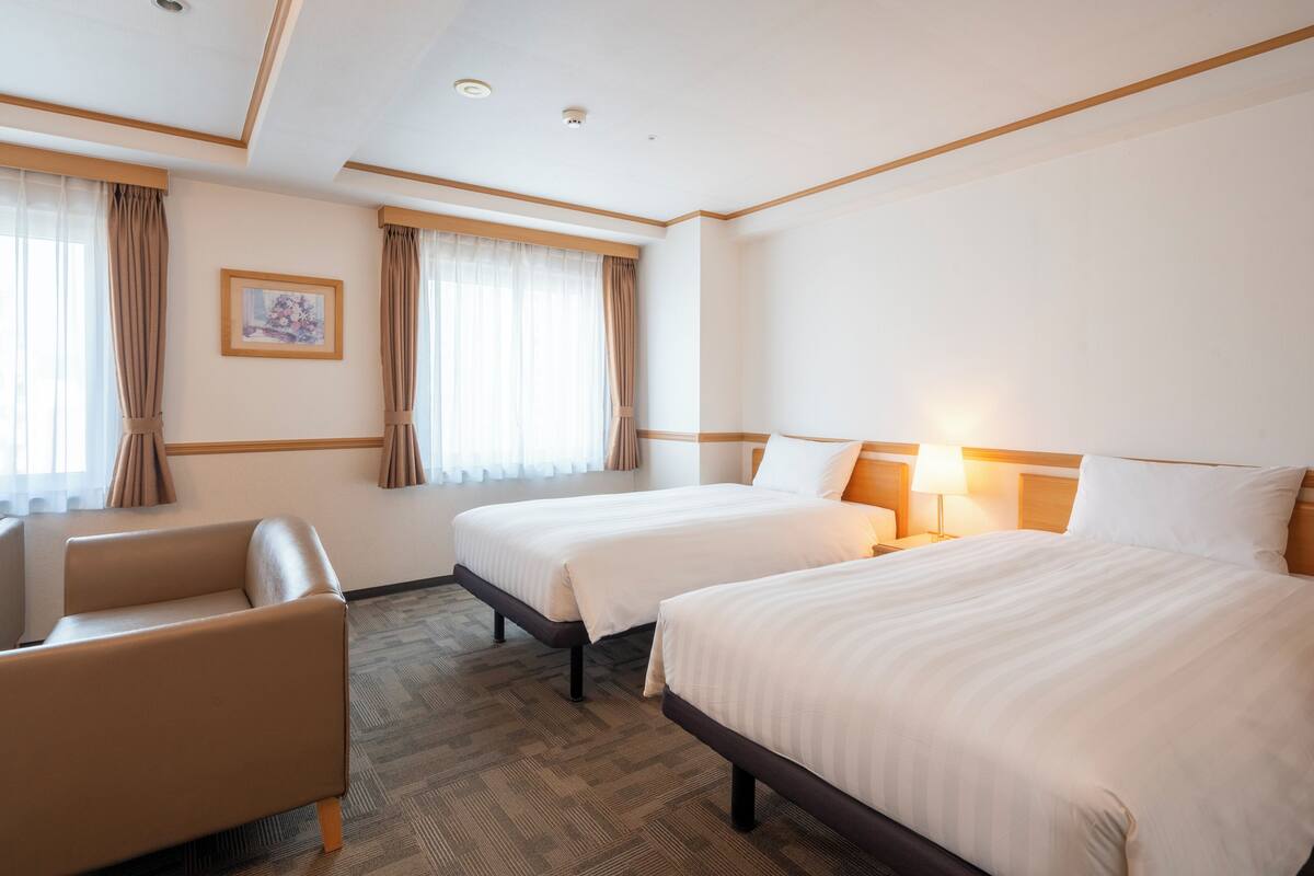A hotel room with two beds, a sofa, and a picture on the wall.