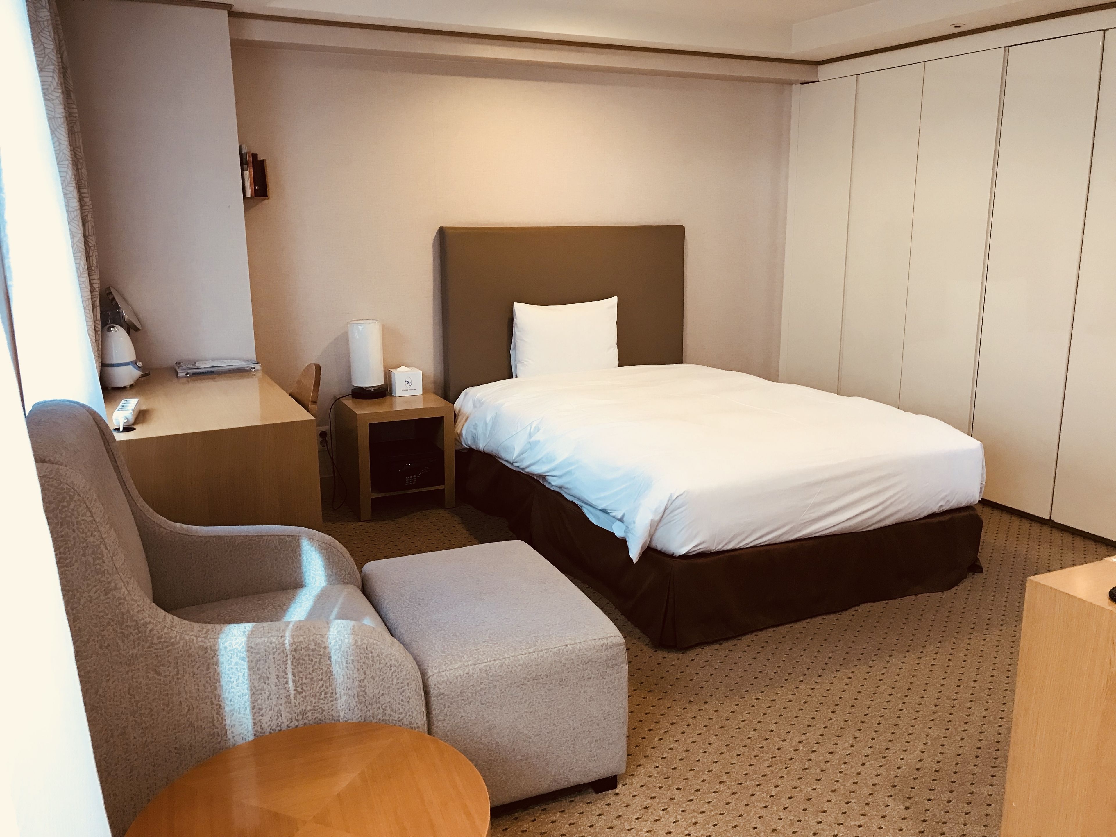 Een hotelkamer met een bed, een bureau, een stoel en een kledingkast.