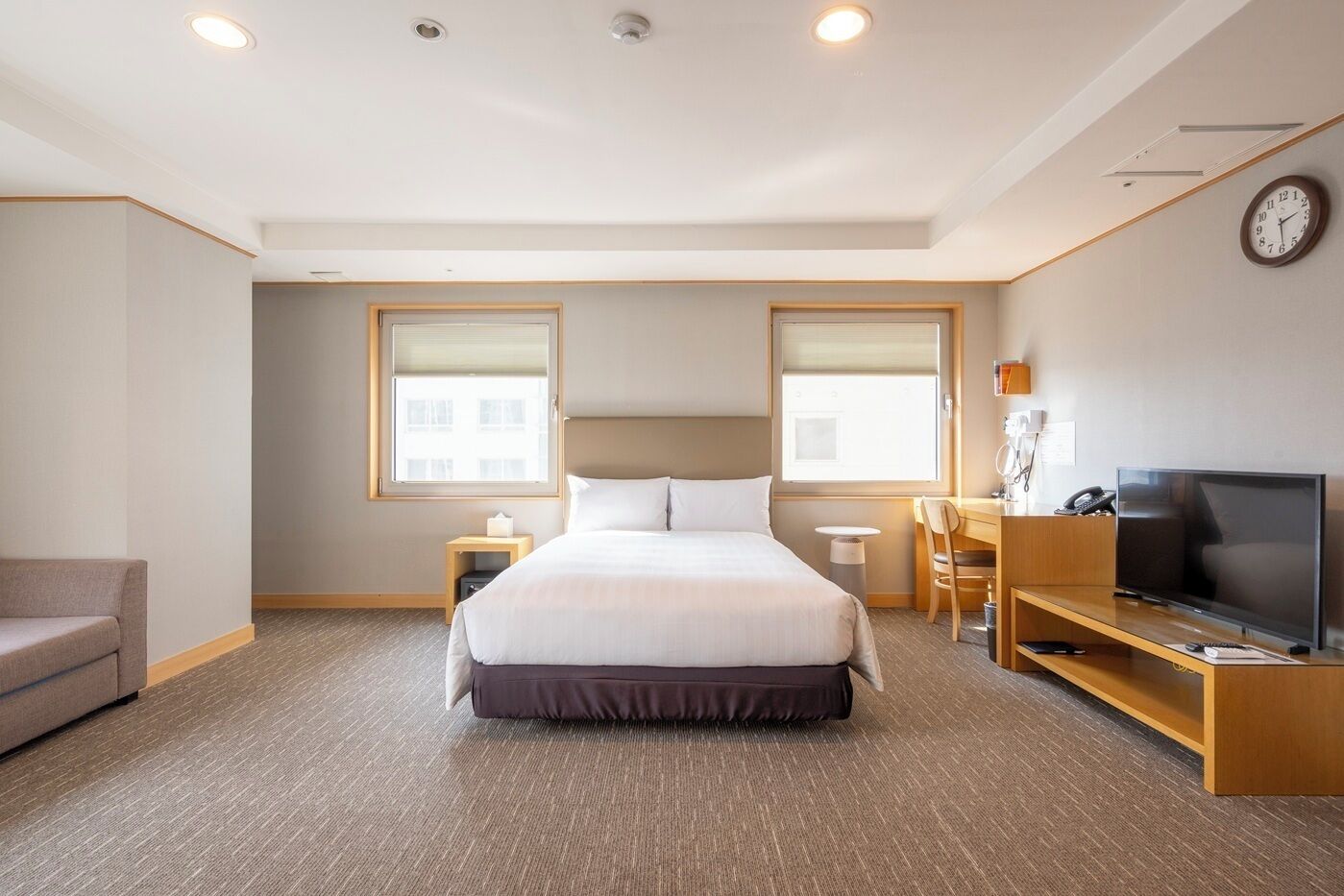 A hotel room with a bed, a TV, a desk, and a chair.