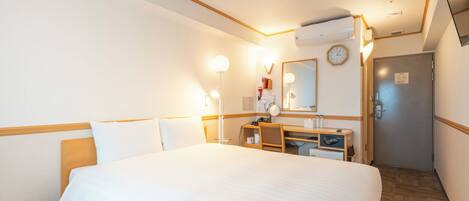 Ein Hotelzimmer mit einem großen Bett, einem Schreibtisch mit Stuhl, einem Spiegel und einer Wanduhr.