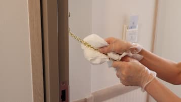 Une personne nettoie une poignée de porte avec un chiffon.