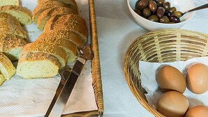 Rebanadas de pan, un cuenco de aceitunas y una cesta de huevos sobre una mesa.