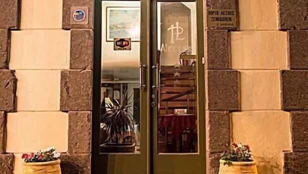La entrada de un edificio con un letrero que dice "PORTO L'ESVOS" y una puerta de cristal que refleja un cielo estrellado.