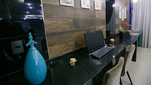 Een modern receptiebalie met een laptop, een vaas en ingelijste foto's aan de muur.