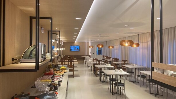 Een modern restaurant met een lange toonbank, meerdere tafels en hangende吊灯.