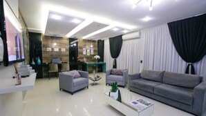 Een moderne woonkamer met een bank, fauteuils, een salontafel en een televisie.