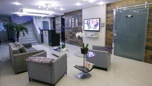 Een moderne lobby met een receptiebalie, een zithoek en een trap.