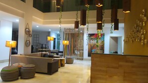 A spacious living area with a high ceiling, modern furniture, and hanging plants. - Hotel Unión Plaza Moteria (Monteria)