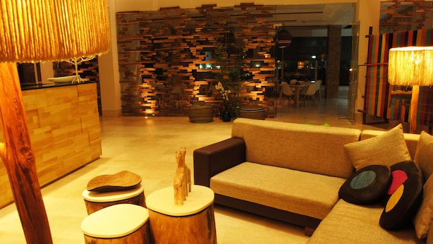 A modern living room with a sofa, wooden side tables, and a decorative wall. - Hotel Unión Plaza Moteria (Monteria)