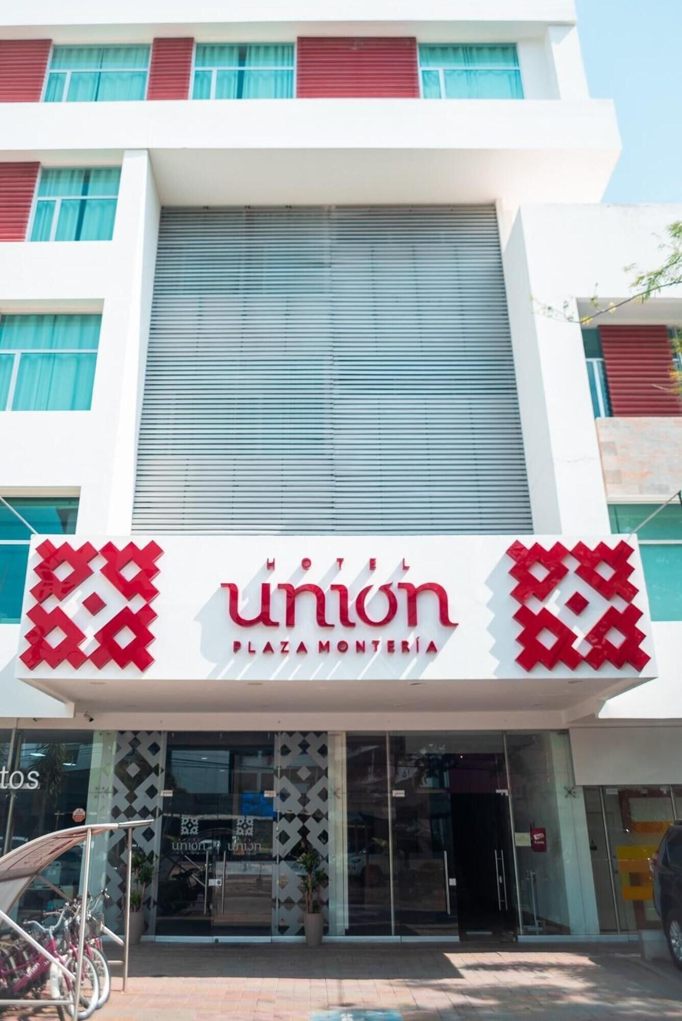 Un hotel llamado 'Union Plaza Montería' con una fachada moderna, amplias ventanas y una entrada destacada.