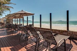 A beachside patio with wicker chairs and umbrellas, overlooking the ocean. - Pietra Flat (Florianópolis)
