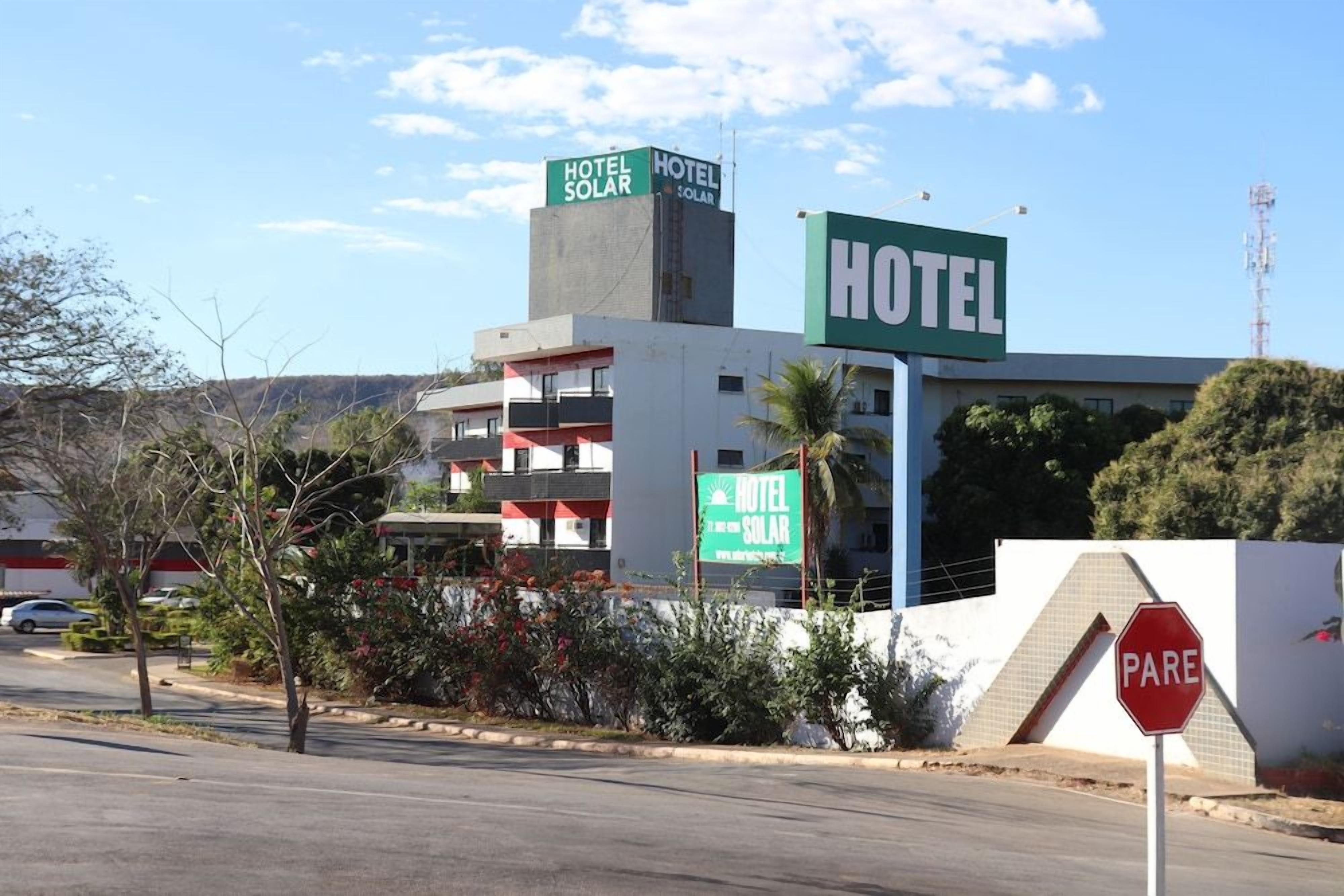 A hotel with a prominent sign, a stop sign, and a building with balconies.