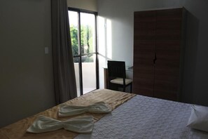 A hotel room with a bed, a chair, a wardrobe, and a view through a large window. - Solar Das Mangueiras Hotel (Barreiras)
