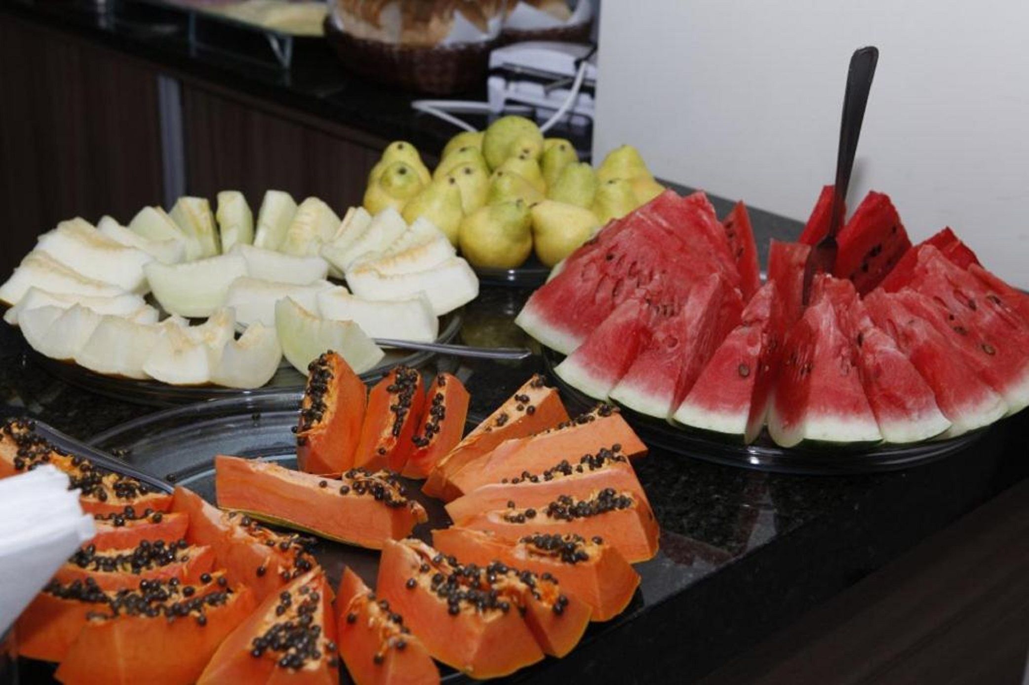 Ein Buffet mit geschnittenen Früchten, darunter Wassermelone, Papaya und Birnen.
