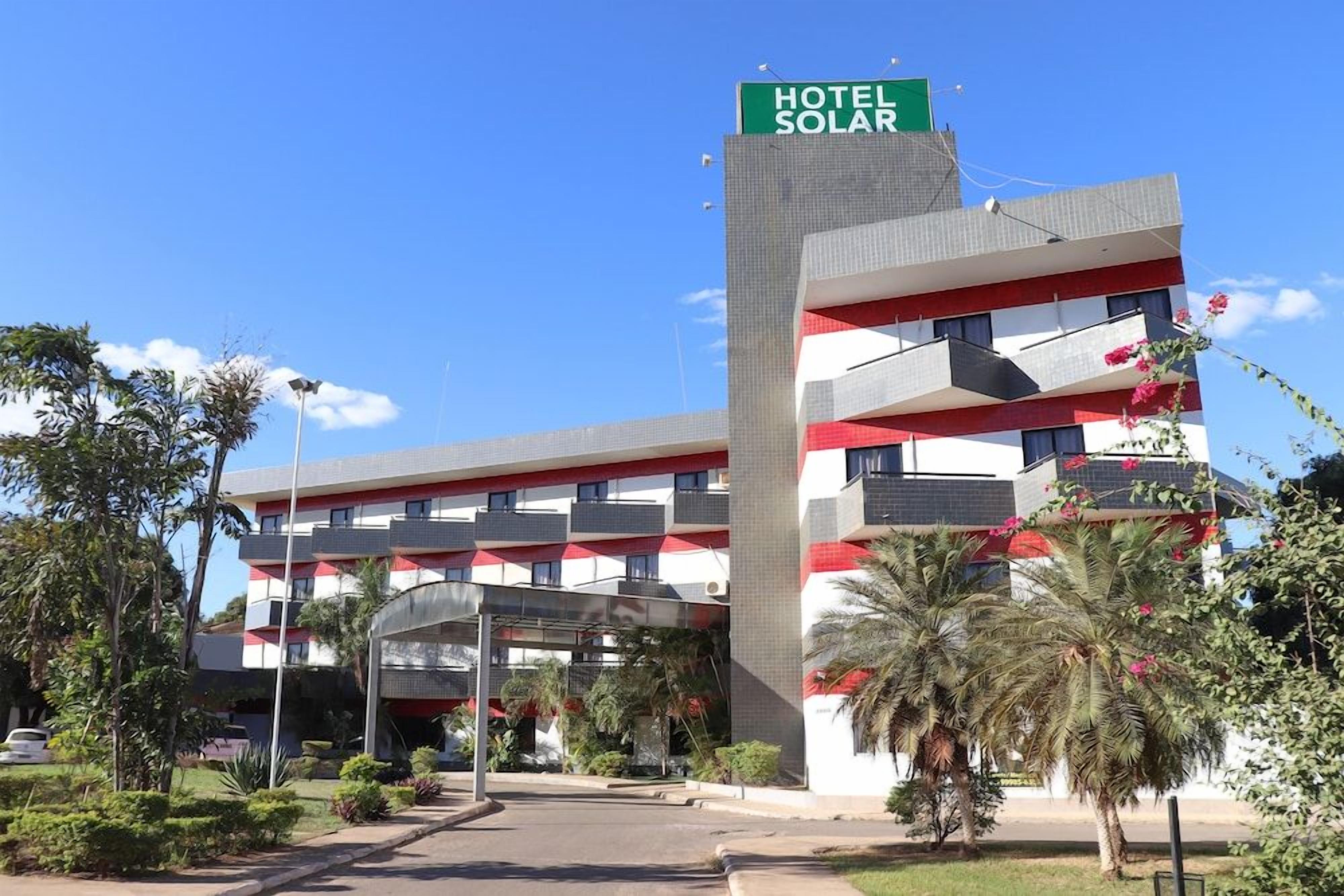 Een hotel met een opvallend bord, meerdere balkons en een overdekte ingang.
