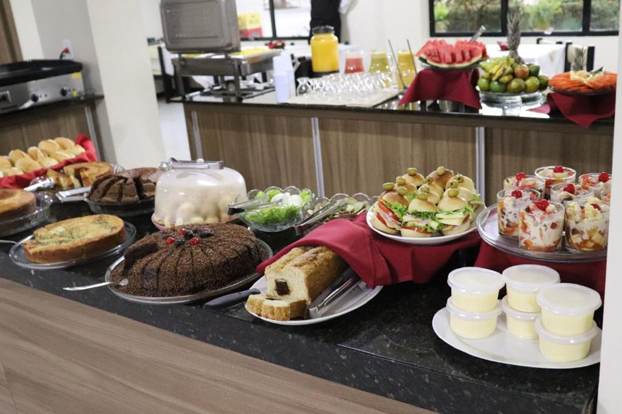 A buffet with various food items including cakes, bread, and fruit.